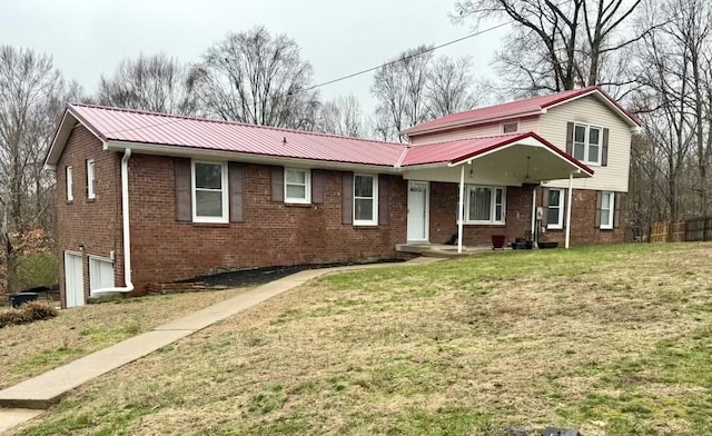 view of front of property featuring a garage, a front yard, metal roof, and brick siding