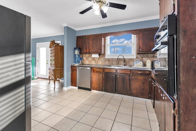 kitchen with light tile patterned floors, a sink, appliances with stainless steel finishes, tasteful backsplash, and crown molding