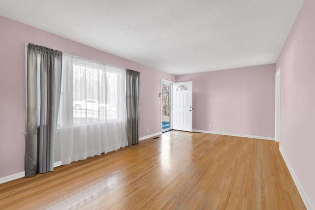 spare room with baseboards and light wood finished floors