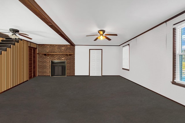 unfurnished living room with carpet floors, a wealth of natural light, beam ceiling, and a fireplace