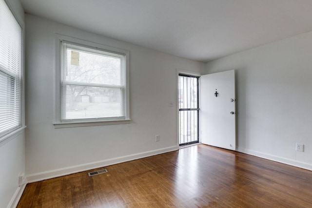 empty room with baseboards, visible vents, and wood finished floors