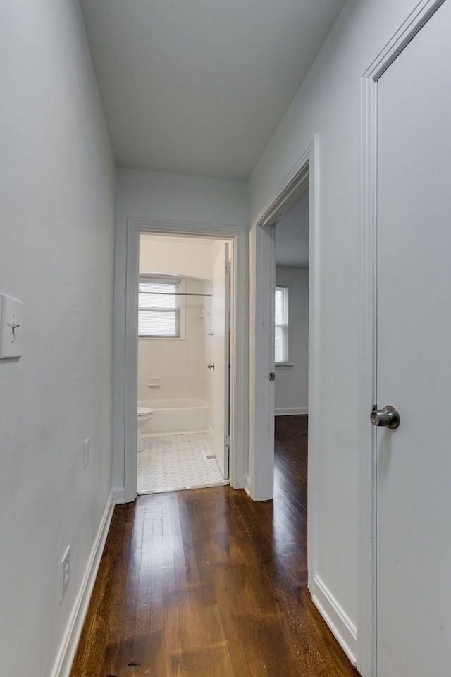 hallway with dark wood-style floors and baseboards