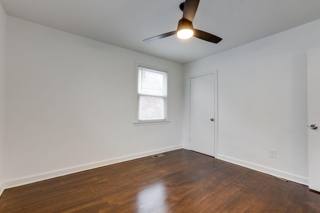 spare room with ceiling fan, dark wood-type flooring, visible vents, and baseboards