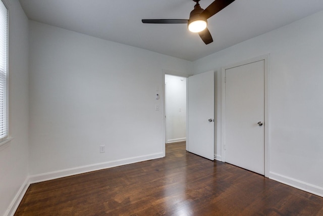 unfurnished bedroom featuring ceiling fan, dark wood-type flooring, and baseboards