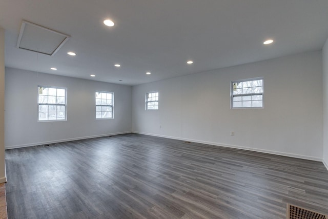 empty room featuring recessed lighting, visible vents, attic access, dark wood-type flooring, and baseboards