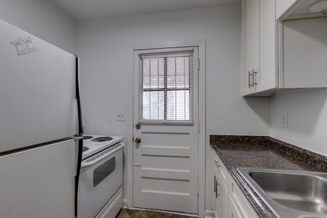 kitchen featuring white appliances, white cabinets, a sink, and dark stone countertops