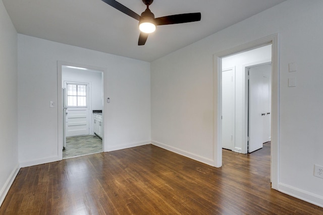 unfurnished room with dark wood-style floors, a ceiling fan, and baseboards