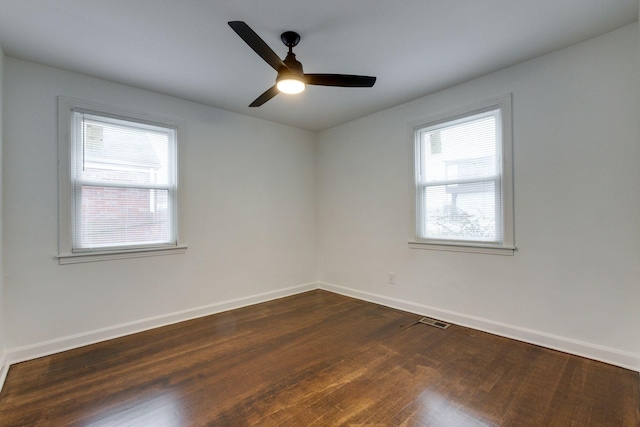 spare room with visible vents, baseboards, ceiling fan, and dark wood-type flooring