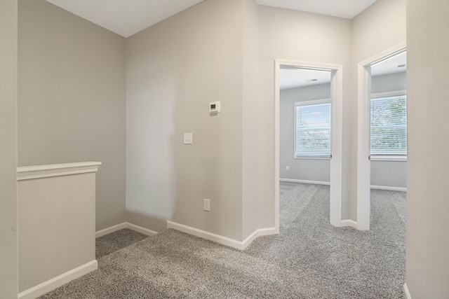 hallway featuring carpet and baseboards