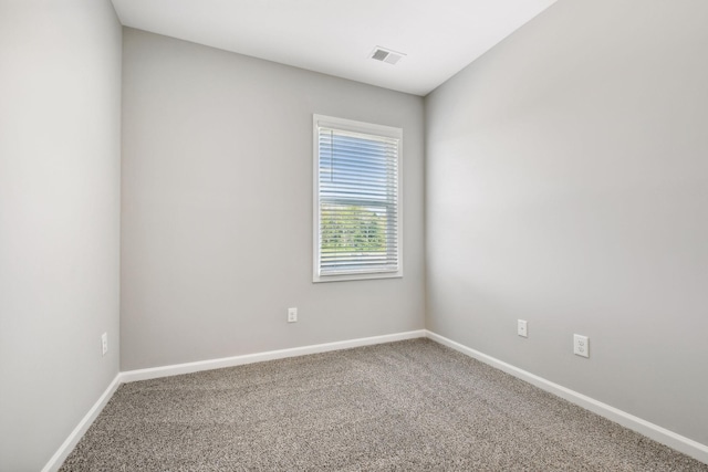 empty room with carpet floors, visible vents, and baseboards