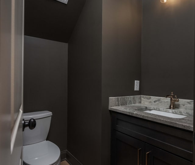 bathroom featuring baseboards, vanity, and toilet