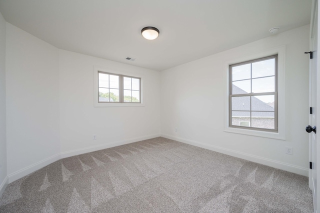 spare room with carpet flooring, visible vents, and baseboards