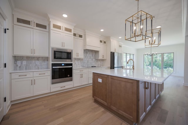 kitchen with white cabinetry, appliances with stainless steel finishes, and a large island with sink