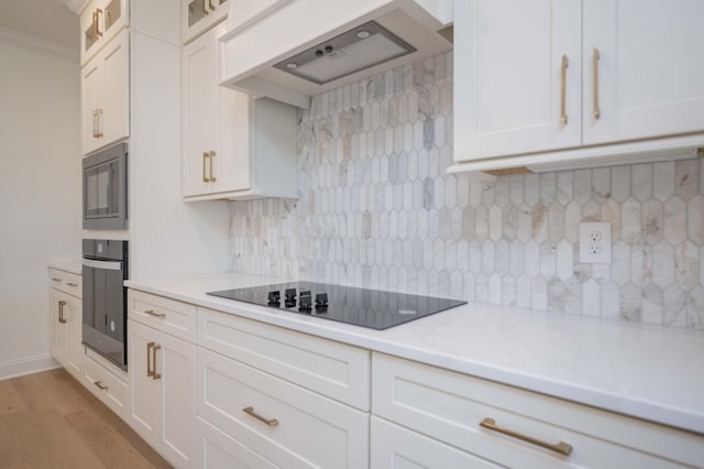 kitchen featuring light countertops, black electric stovetop, glass insert cabinets, and oven