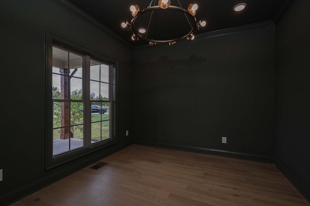 unfurnished room with baseboards, visible vents, wood finished floors, crown molding, and a notable chandelier