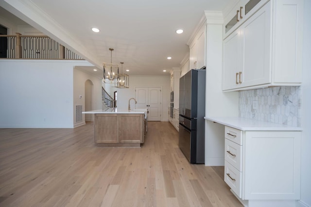 kitchen featuring an island with sink, white cabinets, and freestanding refrigerator