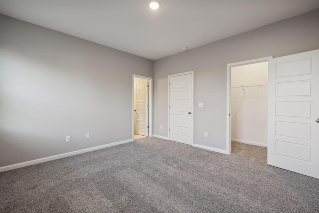 unfurnished bedroom with recessed lighting, carpet flooring, baseboards, a spacious closet, and a closet