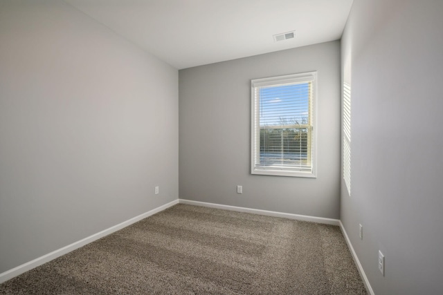 spare room featuring carpet floors, visible vents, and baseboards