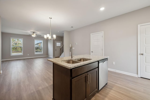 kitchen with dark brown cabinetry, an island with sink, open floor plan, a sink, and stainless steel dishwasher