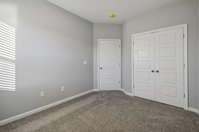 unfurnished bedroom featuring carpet floors, a closet, and baseboards