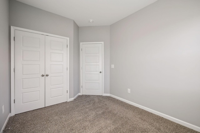 unfurnished bedroom with a closet, baseboards, and carpet flooring