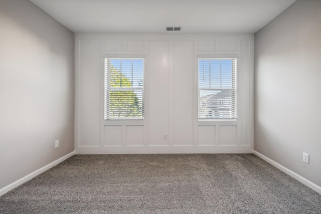 unfurnished room featuring carpet flooring, visible vents, and a decorative wall