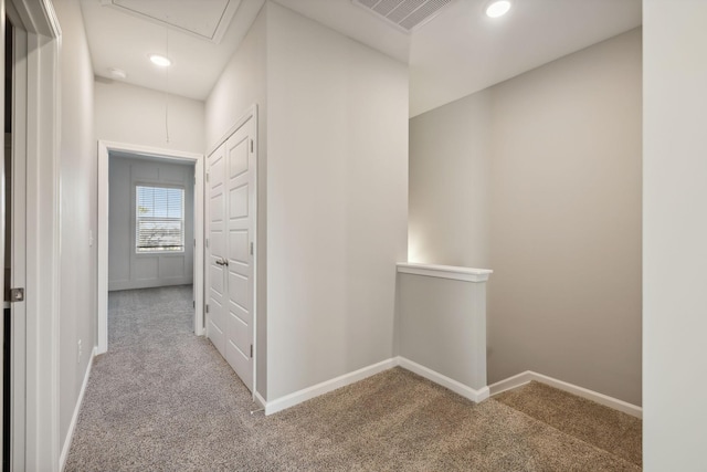 corridor with carpet, attic access, baseboards, and an upstairs landing