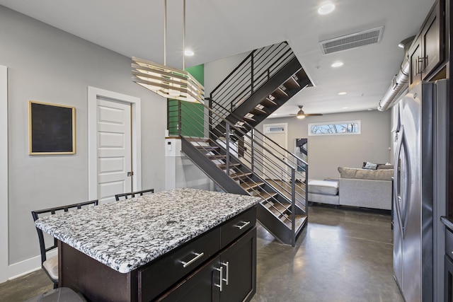 kitchen with visible vents, finished concrete floors, freestanding refrigerator, open floor plan, and a kitchen island