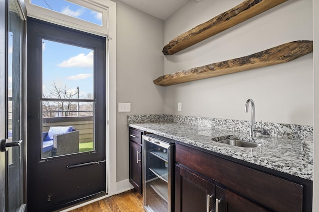 bar with light wood-style floors, wine cooler, a wealth of natural light, and a sink