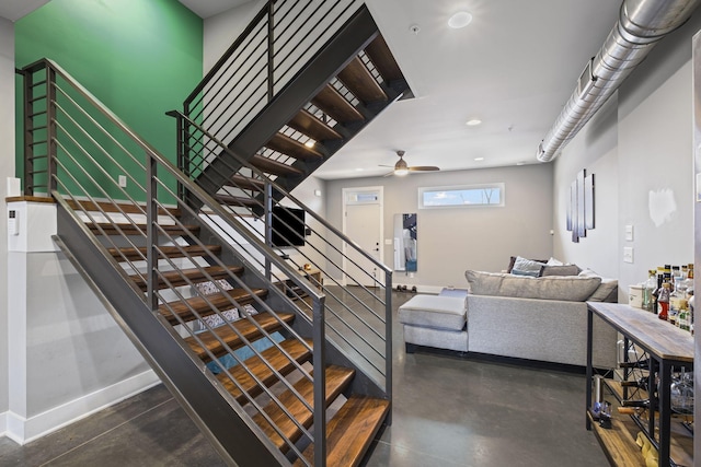 stairway featuring ceiling fan, finished concrete floors, and baseboards