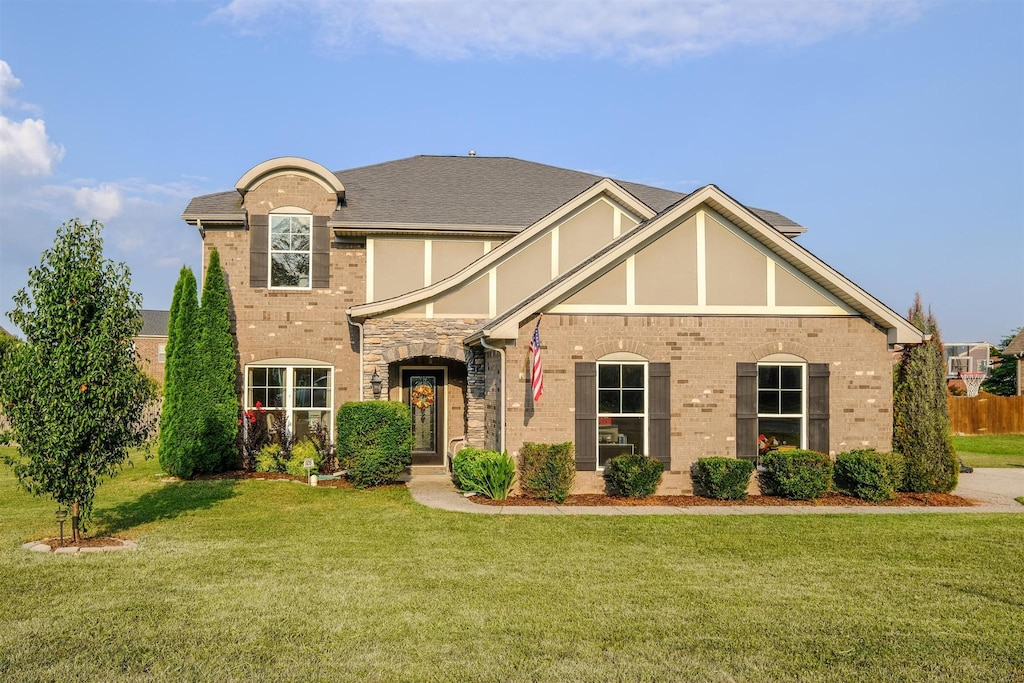 view of front of house with a front yard, brick siding, and stucco siding