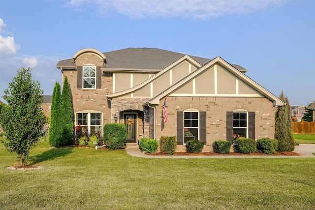 view of front of house with a front yard, brick siding, and stucco siding