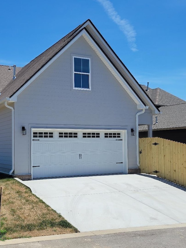 view of property exterior with a garage, fence, and concrete driveway