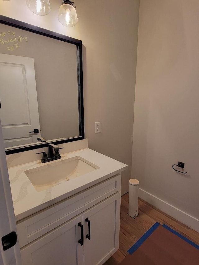 bathroom with baseboards, wood finished floors, and vanity