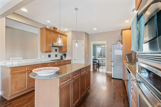 kitchen with a kitchen island, appliances with stainless steel finishes, decorative backsplash, dark wood finished floors, and pendant lighting