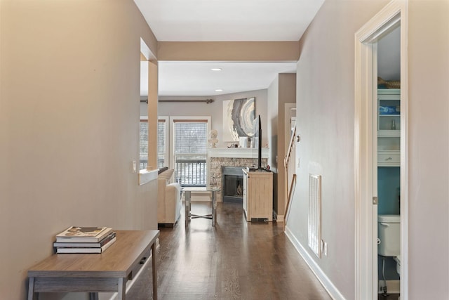 hallway featuring dark wood-style flooring, visible vents, and baseboards