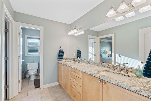 ensuite bathroom featuring tile patterned flooring, a sink, toilet, and connected bathroom