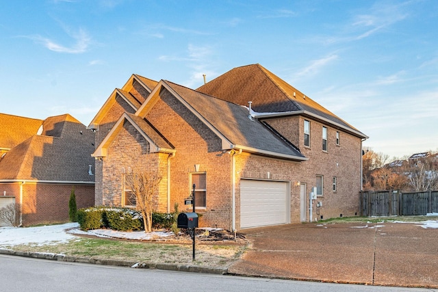 view of front of property with brick siding, roof with shingles, concrete driveway, fence, and a garage