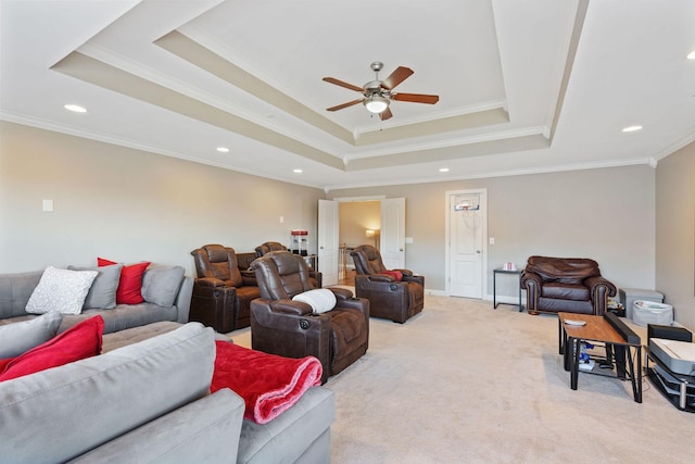 living room featuring a ceiling fan, a tray ceiling, light colored carpet, and baseboards