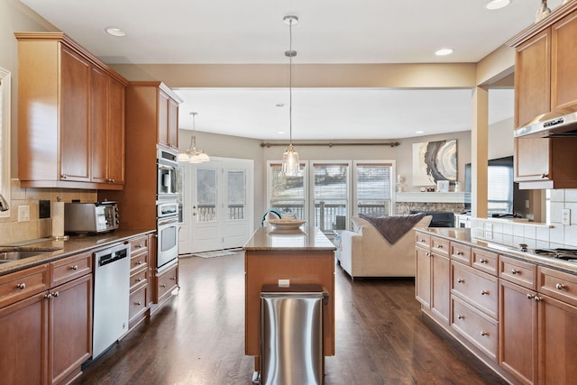 kitchen featuring a center island, pendant lighting, tasteful backsplash, stainless steel dishwasher, and open floor plan