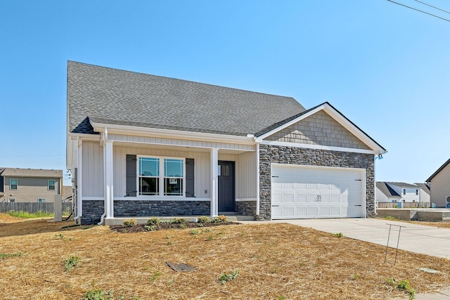 craftsman-style house with a garage, fence, stone siding, driveway, and roof with shingles