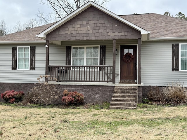 bungalow-style home featuring a porch, roof with shingles, and a front yard