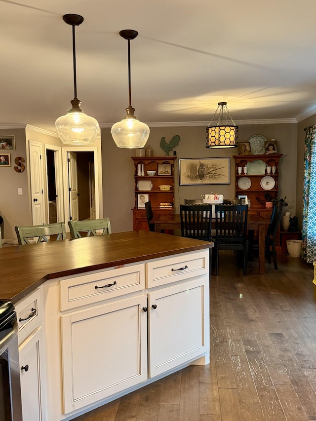 kitchen with ornamental molding, butcher block counters, white cabinets, and hanging light fixtures