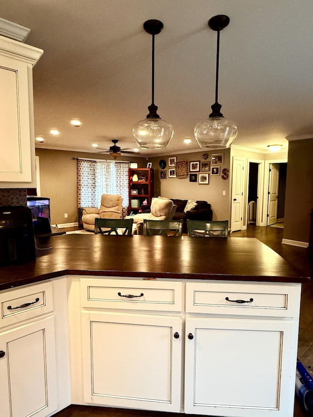 kitchen featuring dark countertops, white cabinets, open floor plan, and hanging light fixtures