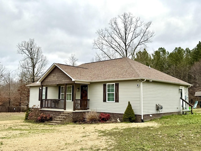 ranch-style home featuring covered porch, a shingled roof, crawl space, and a front yard