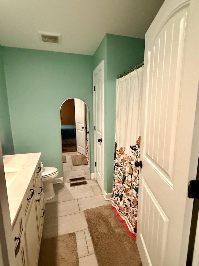 bathroom with toilet, tile patterned flooring, visible vents, and vanity