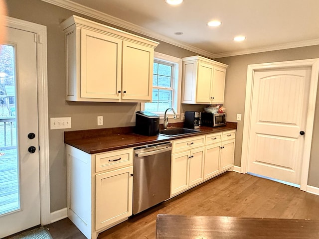 kitchen featuring dark countertops, wood finished floors, stainless steel appliances, crown molding, and a sink