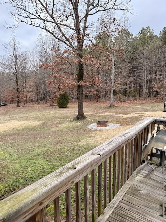 wooden terrace featuring an outdoor fire pit and a lawn