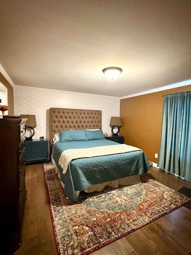 bedroom featuring ornamental molding, an accent wall, dark wood-style floors, and wallpapered walls