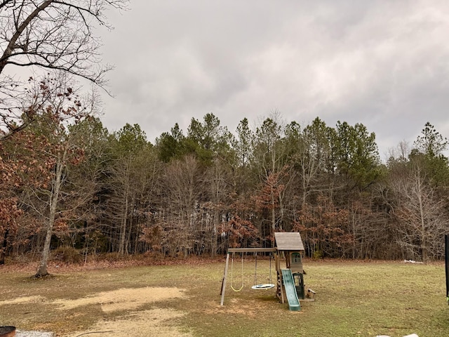 view of yard featuring a forest view and a playground